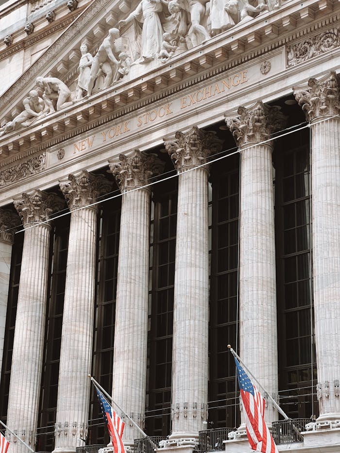 Detailed view of the iconic New York Stock Exchange facade with American flags and columns.